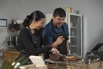Two people examining electronic components together at a workbench in an office setting